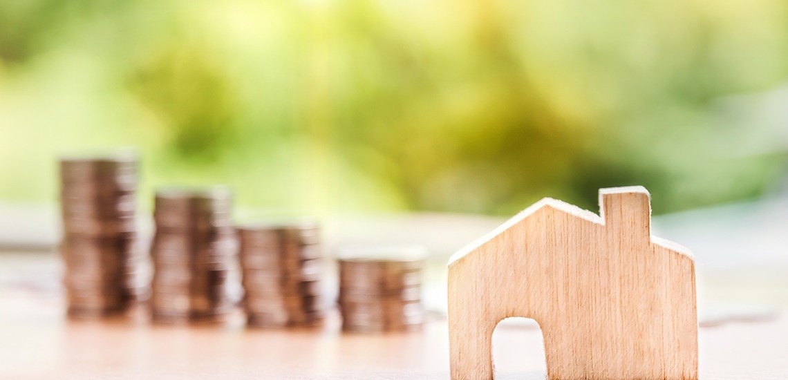 stack of coins increasing next to small wooden house