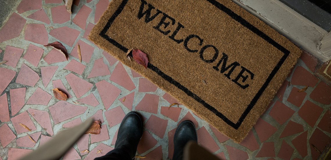 Person standing in front of welcome mat