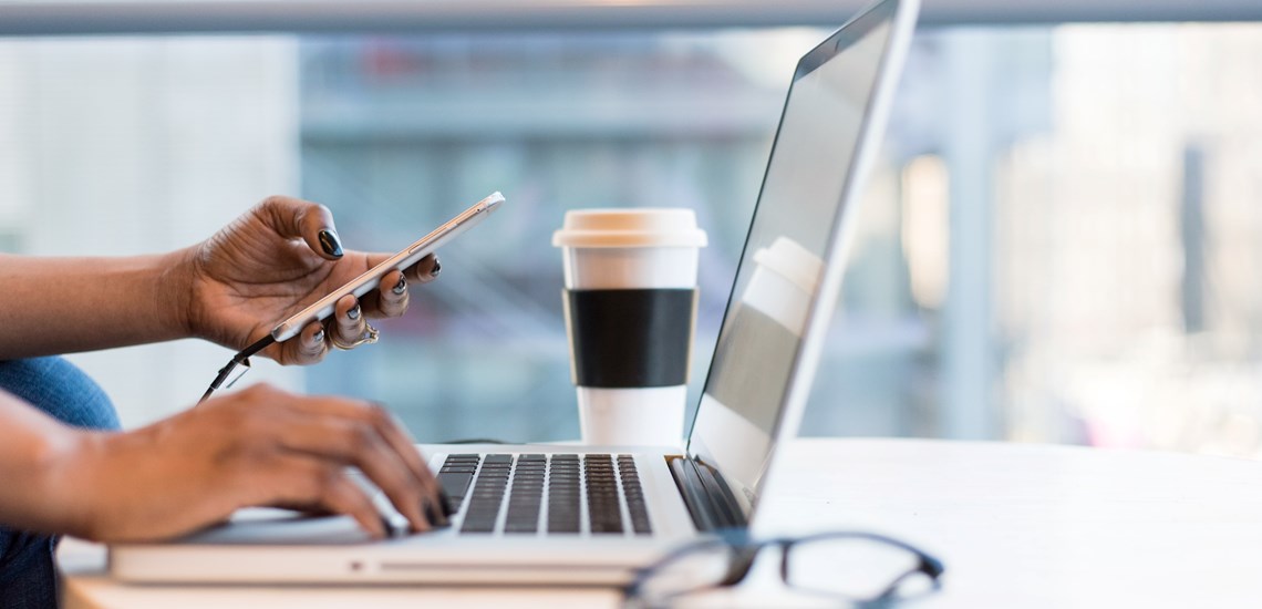 person working at coffee table with laptop coffee cup and glasses