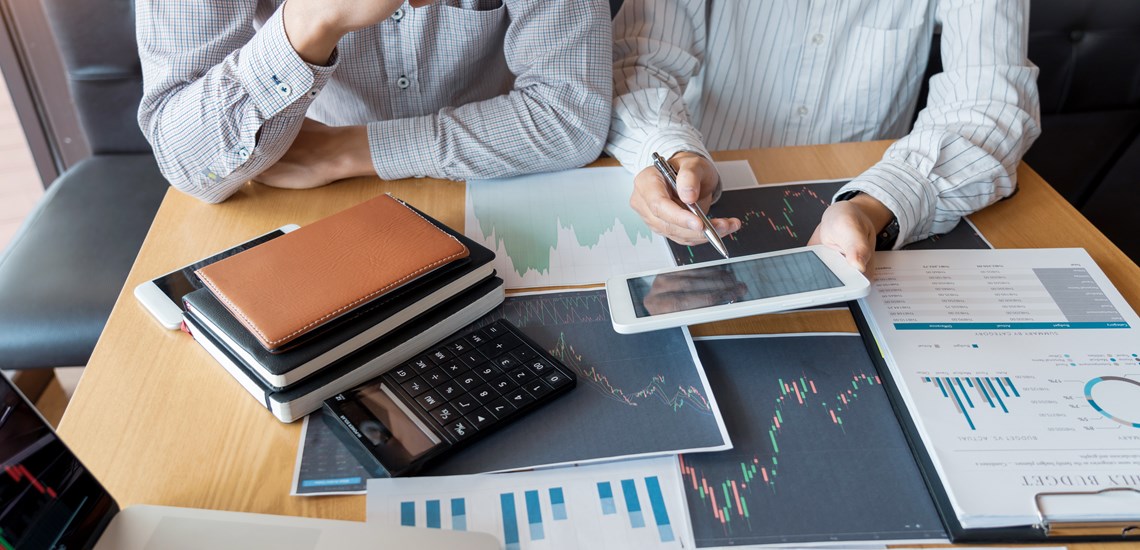 financial adviser helping client manage money with graphs and technology