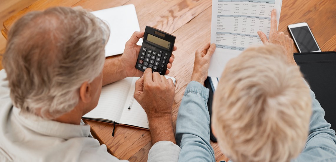 Two people holding a calculator and sheets of paper