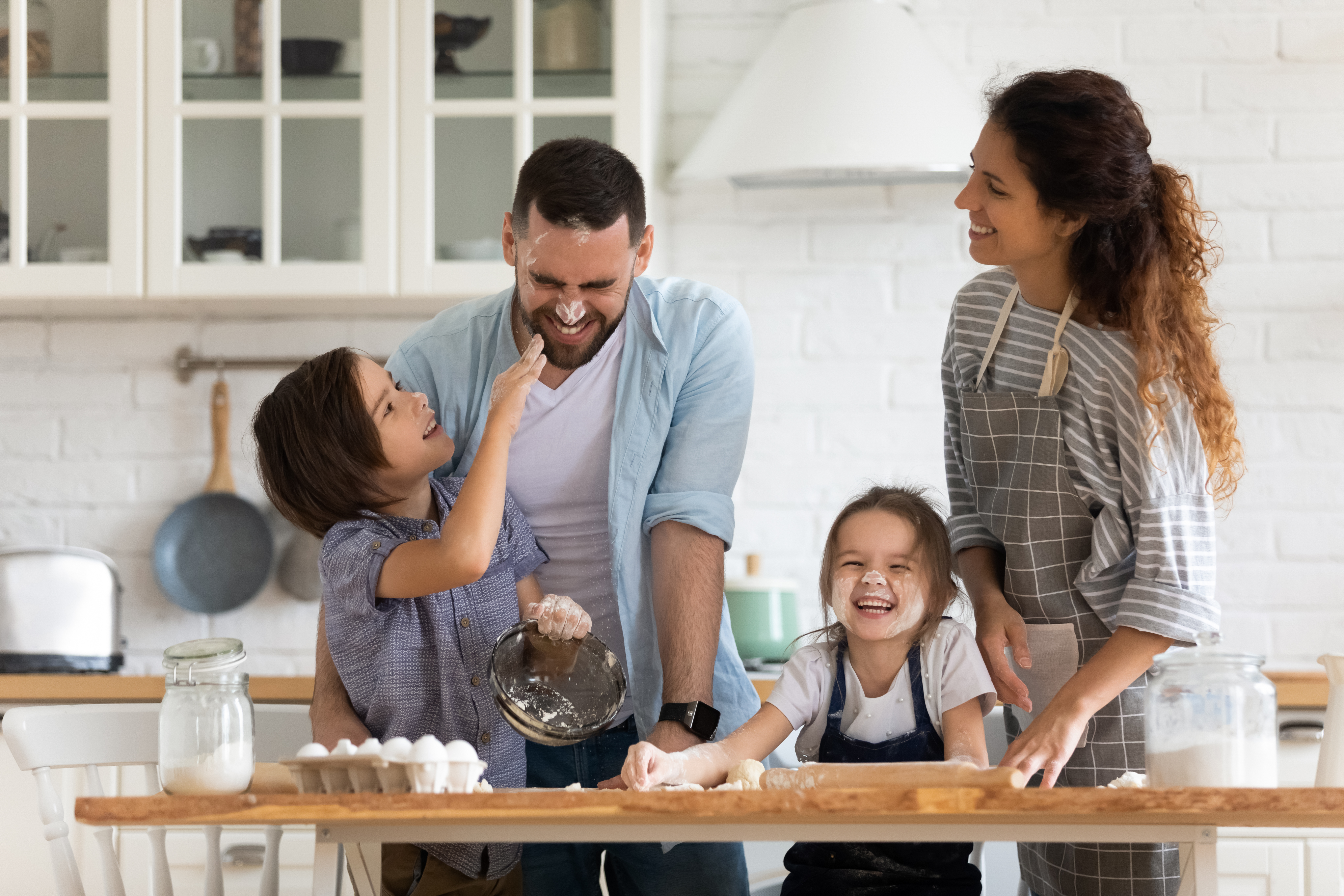 Two adults and two children standing in a kitchen. Display purpose for Just Mortgages Life Insurance for a Mortgage