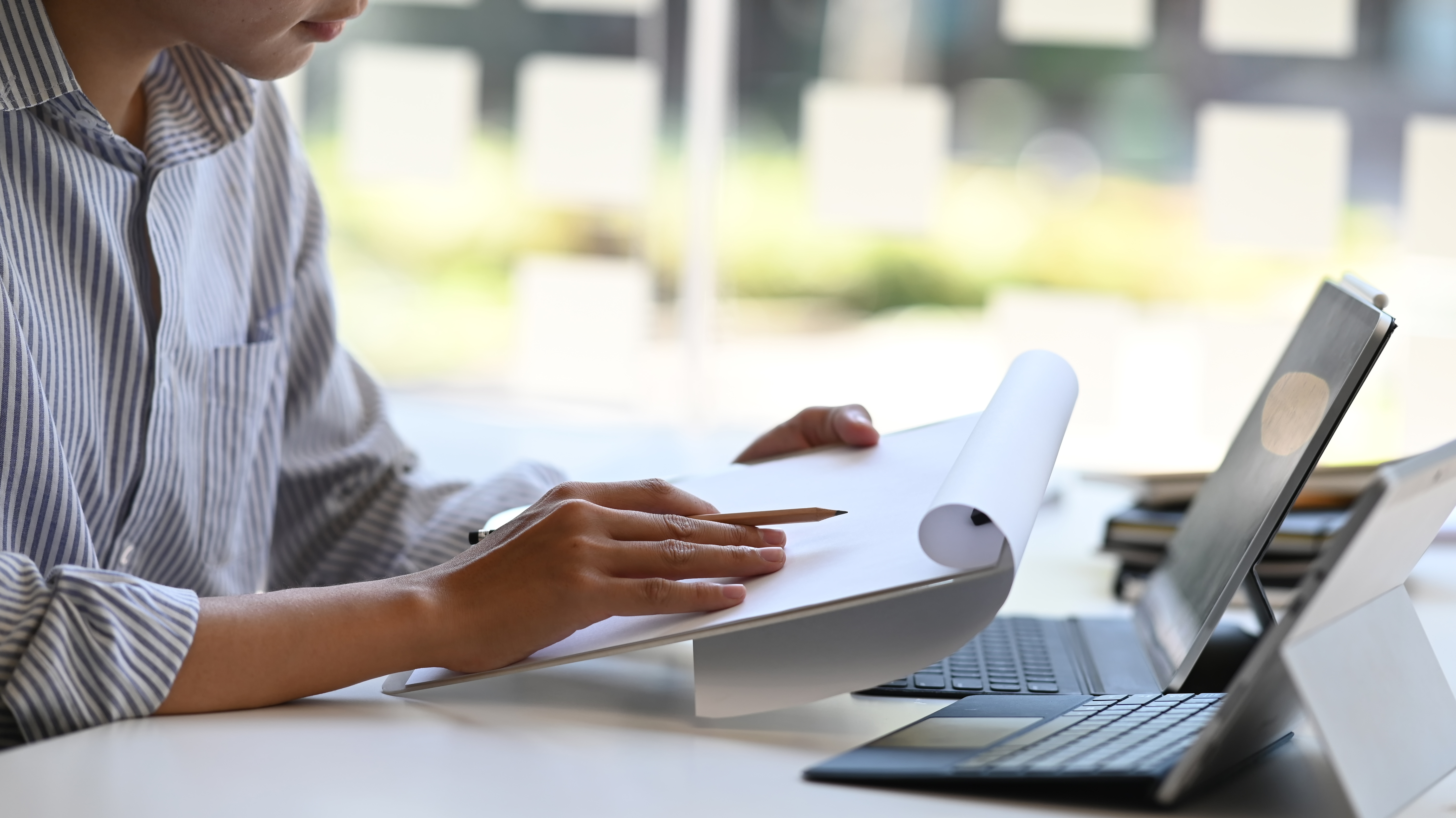 person sitting at a table with a laptop on, looking at papers